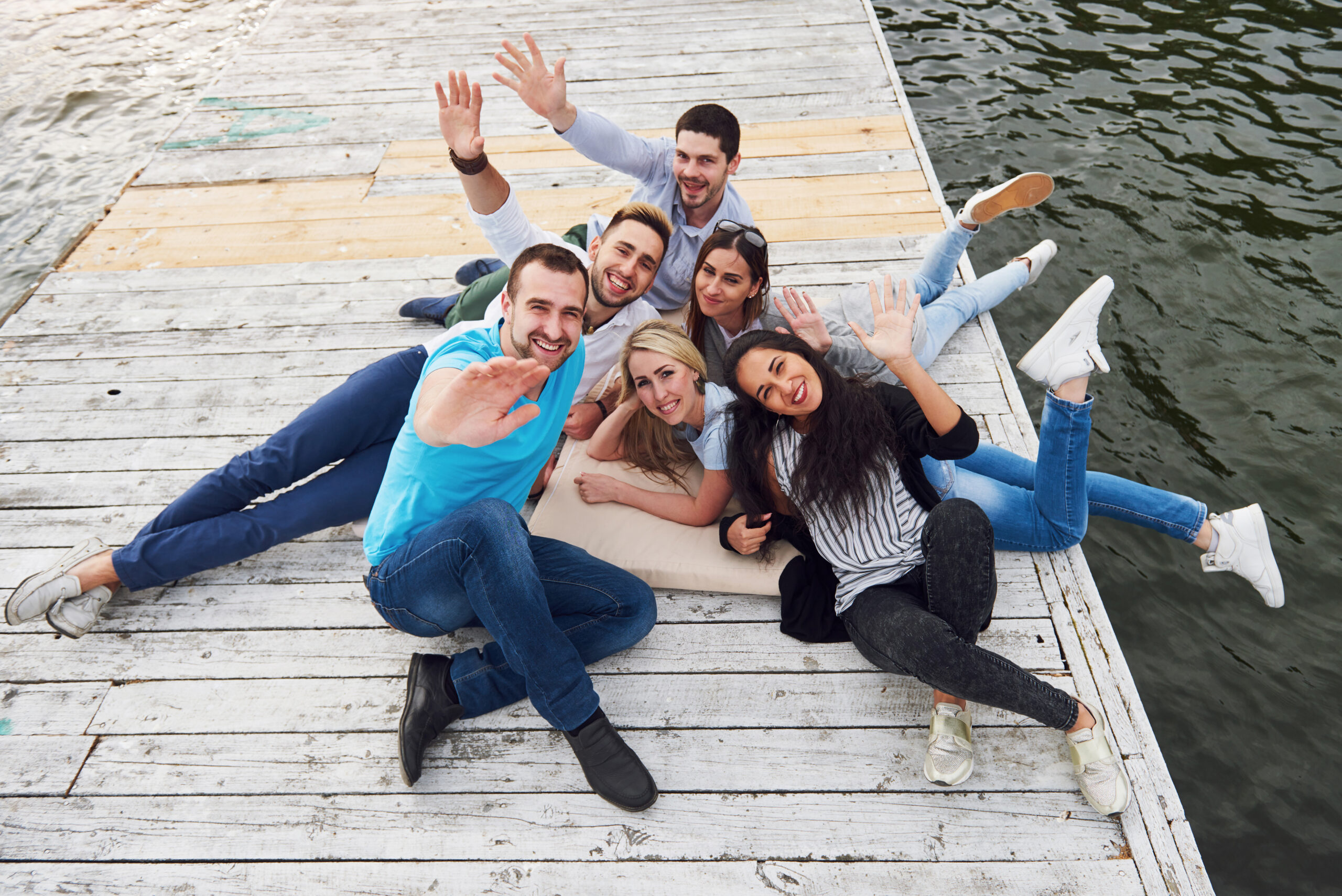 Group of beautiful young people on the pier, friends satisfaction creates emotional life